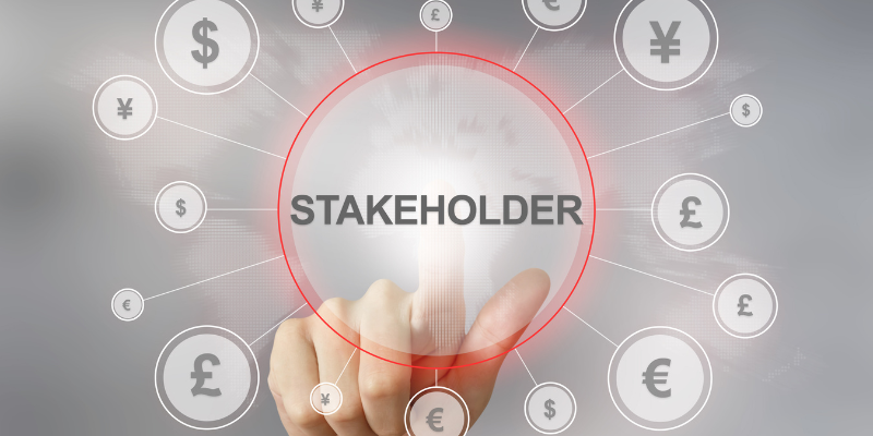 A holographic image with bubbles of currency symbols surrounding the word "stakeholder", and a finger points to the word