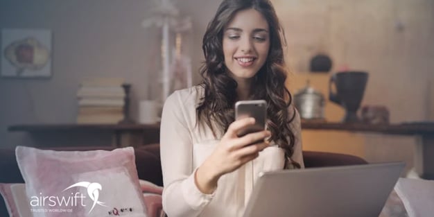 Young caucasian woman sitting on a sofa using laptop and smarthphone.