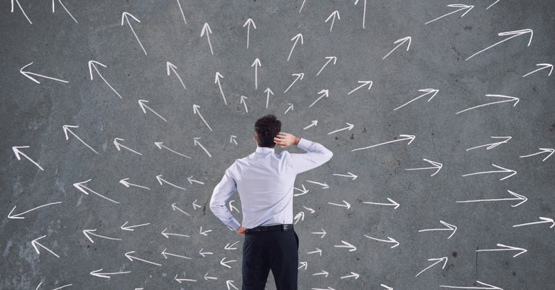 Man contemplating a wall filled with arrows pointing at different directions.