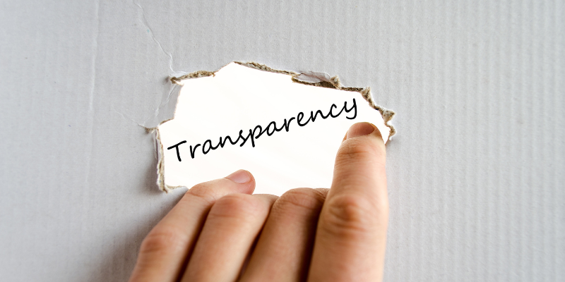 A hand on the foreground ripping a hole into a cardboard box to reveal the word "transparency"