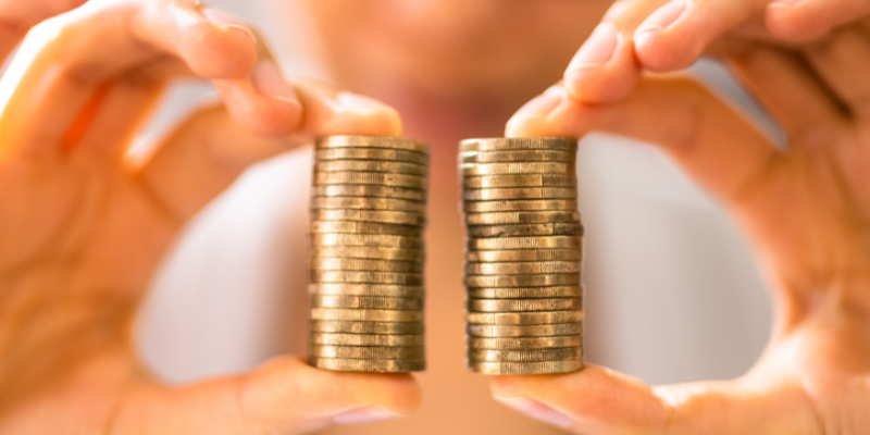 A person holding two stacks of coins in between the thumb and index fingers of each hand