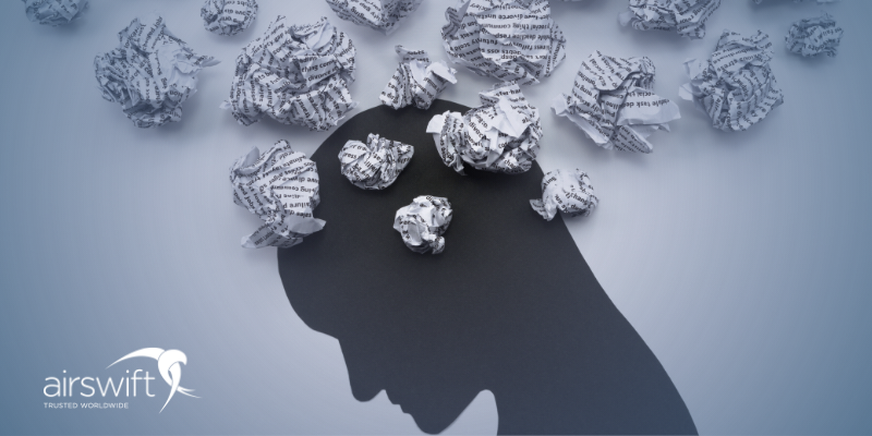 Silhouette of a person's head with crumpled paper balls scattered around