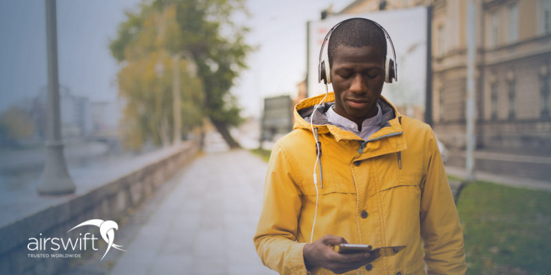 microlearning - 3Man listening to audio while walking outdoors, wearing headphones