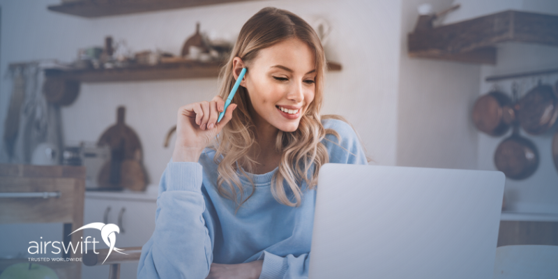 Woman studying online with a laptop at home, smiling.