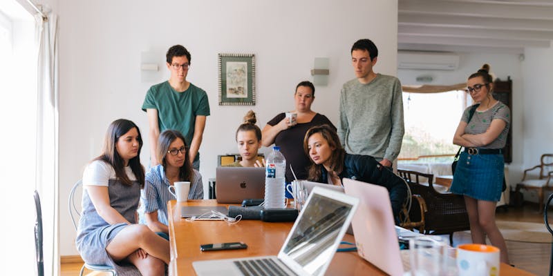 A group of young employees gathered around a laptop