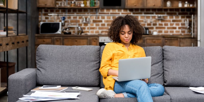 young woman sitting on a couch working on her laptop