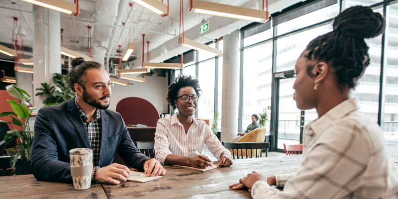 Diverse hiring panel interviewing a candidate in a modern office setting with large windows